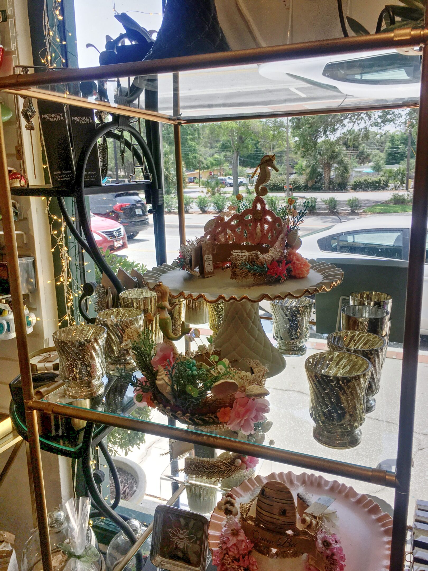 Decorative cupcakes and mugs on display shelf.